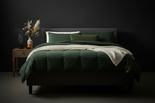 Deep forest green comforter draped over a dark bed with amber candlelight and dried botanicals